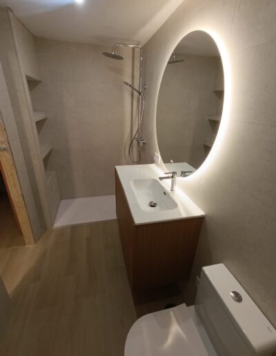 Detalle de baño reformado con espejo redondo iluminado